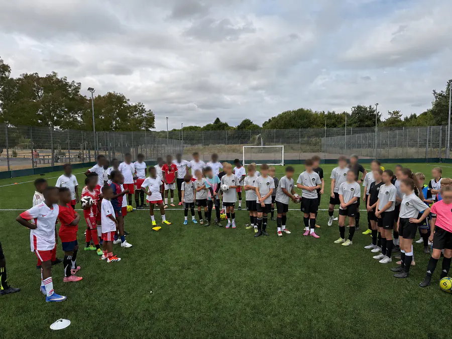 Young football teams gathered together beside the pitch